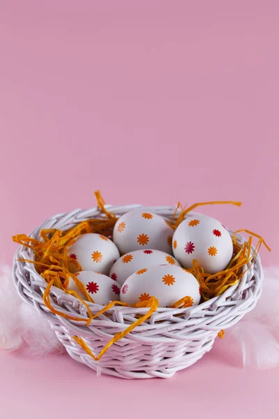 Uova di Pasqua nel nido e cesto su sfondo rosa — Foto Stock
