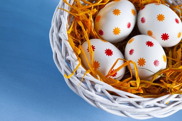 Quatro ovos de Páscoa na cesta em fundo azul — Fotografia de Stock