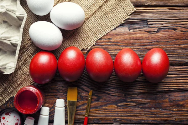 Paskalya yumurtaları, boya ve ahşap masa üzerinde fırçalar — Stok fotoğraf