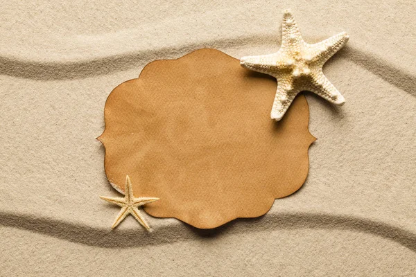 Blått papir-etikett og sjøstjerner på strandsand – stockfoto