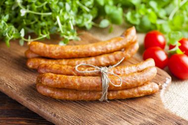 Çiğ sosis, domates ve ahşap üzerinde taze otlar ve tuval backgro