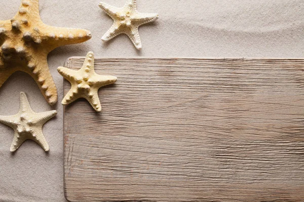 Estrella de mar y tablero de madera en arena de playa — Foto de Stock