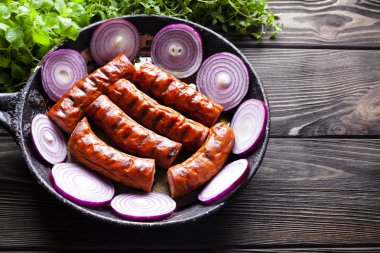 Izgara sosis tava ve ahşap masa üzerinde taze otlar
