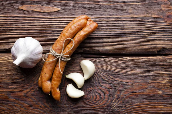 Сырая колбаса и чеснок на деревянном столе — стоковое фото