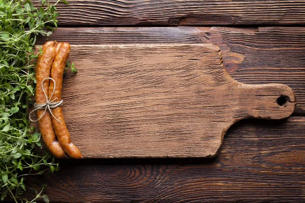 Сырая колбаса и свежие травы на деревянном столе — стоковое фото