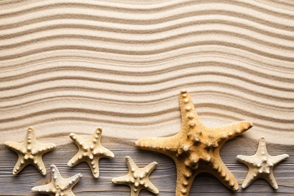 Starfishes e prancha de madeira na areia da praia — Fotografia de Stock