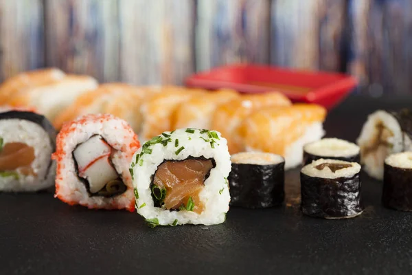 Sushi japonés sobre fondo negro y madera — Foto de Stock