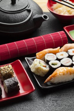 Sushi seti ve siyah masada siyah çaydanlık