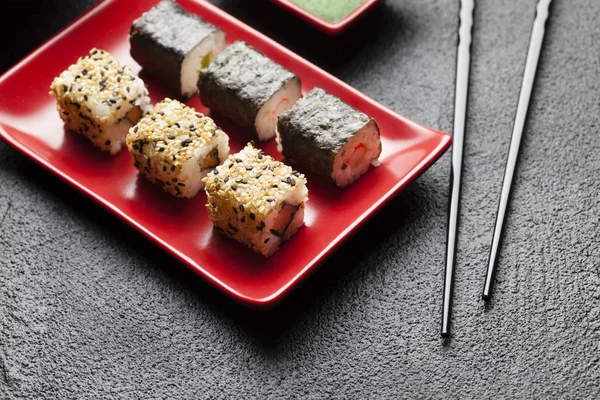 Comida de sushi em prato vermelho e mesa preta — Fotografia de Stock