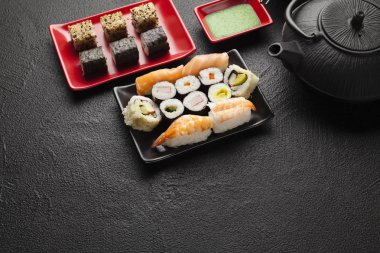 Sushi seti ve siyah masada siyah çaydanlık