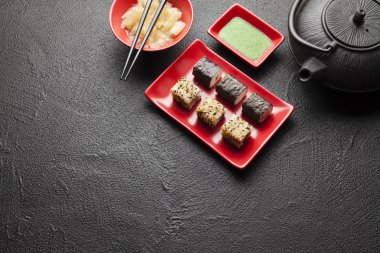 Kırmızı plaka, wasabi ve zencefil ve çaydanlık siyah masada suşi