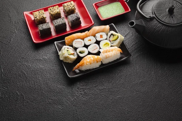 Sushi seti ve siyah masada siyah çaydanlık