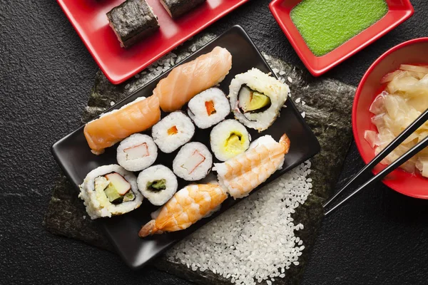 Sushi definido em pratos vermelhos e pretos e fundo de mesa preta — Fotografia de Stock