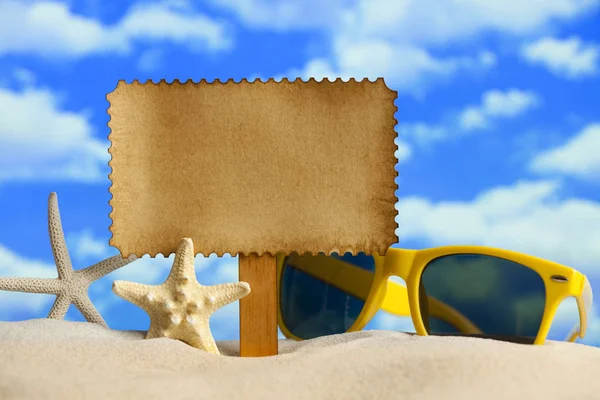 Etiquette en papier, étoiles de mer et lunettes de soleil sur la plage — Photo