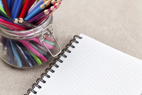 Caderno e lápis de cor em um frasco — Fotografia de Stock