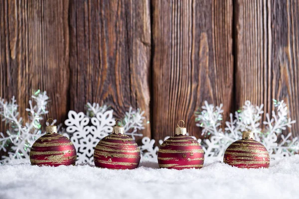 Fondo de Navidad - chucherías y copos de nieve sobre nieve y madera —  Fotos de Stock