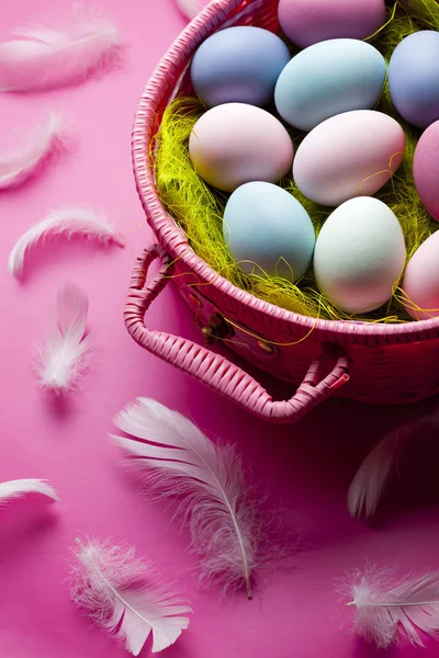 Ovos de Páscoa coloridos e penas sobre fundo rosa — Fotografia de Stock