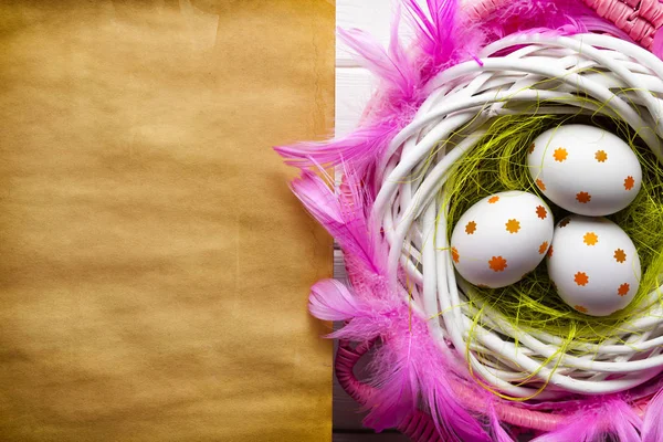 Drei bemalte Ostereier im Nest und blankes Büttenpapier — Stockfoto