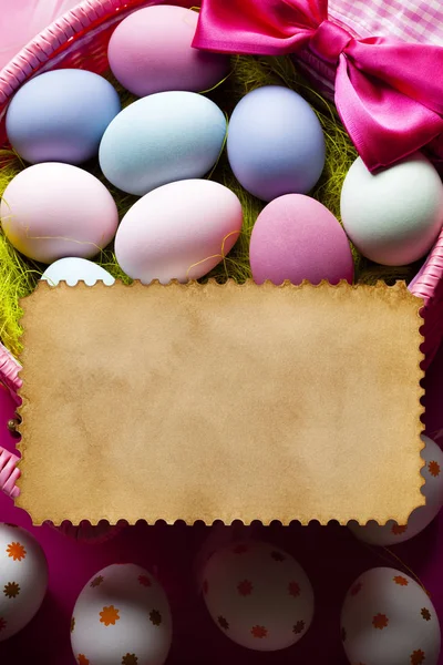 Blank handmade paper sheet and colored Easter eggs in a basket — Stock Photo, Image