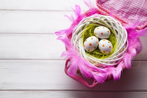 부활절 달걀 둥지에 흰색 나무 테이블에 핑크 바구니 — 스톡 사진