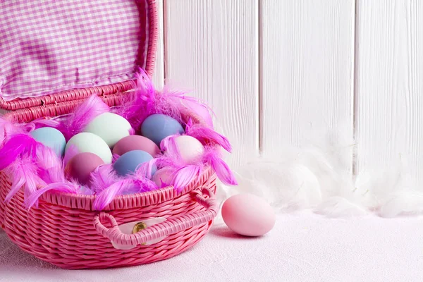 Καλό Πάσχα - ροζ καλάθι γεμάτο χρωματιστά αυγά και φτερά στην — Φωτογραφία Αρχείου