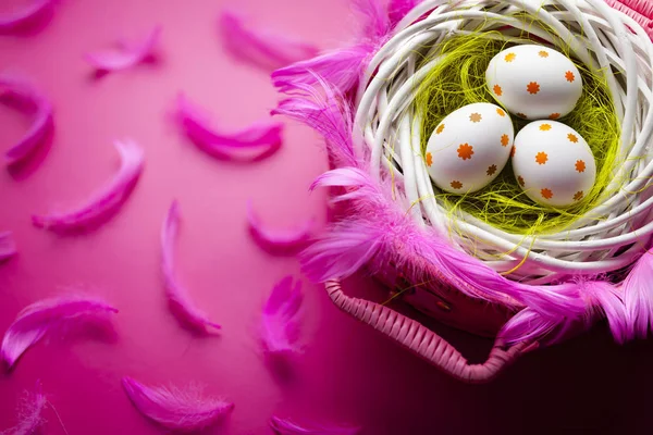 Tre målade påskägg i boet och rosa korg — Stockfoto