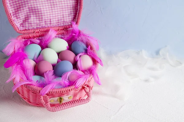 Kellemes Húsvéti Ünnepeket - rózsaszín kosár tele a színes tojásokat és tollak — Stock Fotó