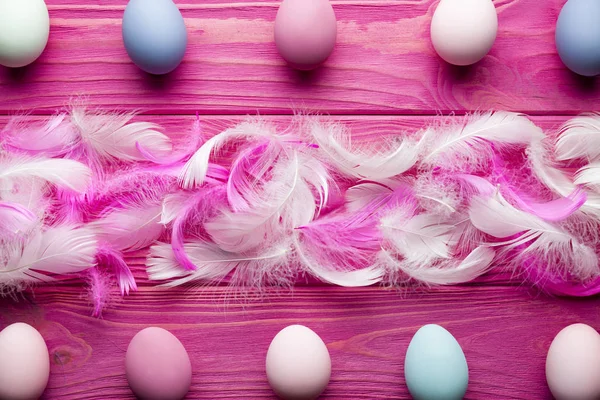 Sfondo pasquale - uova e piume colorate su bac di legno rosa — Foto Stock