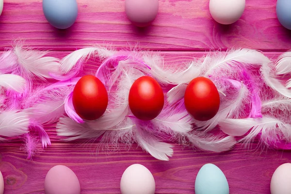 Sfondo pasquale - uova e piume colorate su bac di legno rosa — Foto Stock