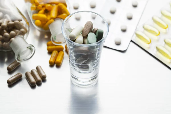 Dose di farmaci e varie capsule e pillole su un dorso d'acciaio — Foto Stock