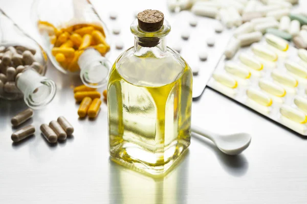 Medicina come sciroppo in una bottiglia di vetro e varie capsule su un — Foto Stock