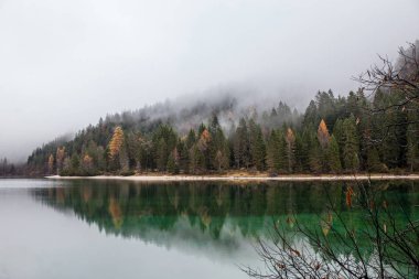 alpine lake in foggy morning in mountains clipart