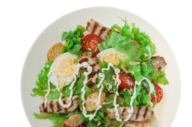 Beyaz arka planda ızgara tavuk filetosu ile Sezar salatası.