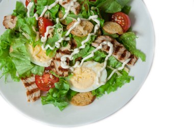 Beyaz arka planda ızgara tavuk filetosu ile Sezar salatası.