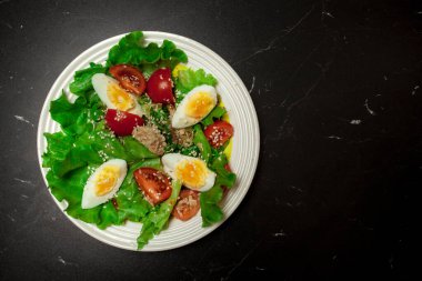 Siyah arka planda tunny balıklı taze salata.