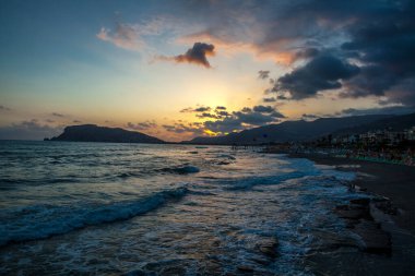 İnanılmaz sahil gün batımı ve inanılmaz köpüklü dalgalar. Arkaplanda tepe.