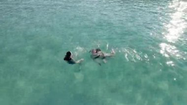 Su yüzeyinde kristal berraklığında yüzen iki güzel genç kadın.