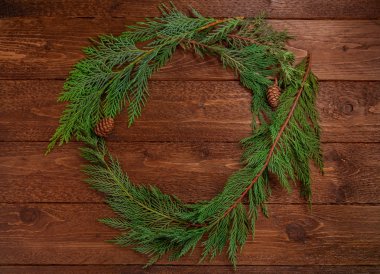 Noel kompozisyonu. Koyu ahşap arka planda Noel ağacı dallarından yapılmış bir çelenk. Noel, kış konsepti. Düz yatış, üst görünüm.