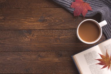 Karanlık ahşap masa üzerinde dekorasyon unsurları, kitap ve akçaağaç yapraklarıyla sonbahar teması. Yaratıcı Düz Düzlem ve Üst Görünüm bileşimi 