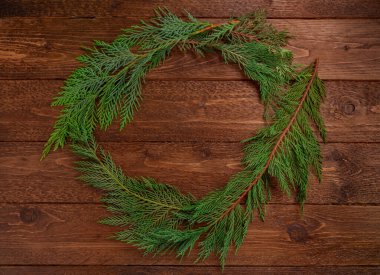 Noel kompozisyonu. Koyu ahşap arka planda Noel ağacı dallarından yapılmış bir çelenk. Noel, kış konsepti. Düz yatış, üst görünüm.