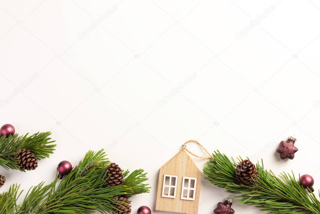 Spruce branches with small wooden house, on a white background. Christmas, winter concept. Flat lay, top view, copy space.