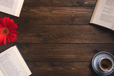 Cozy composition with books. Open books, cup of coffee, flower, on wooden background. Flat lay, top view, copy space.