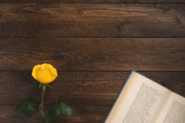 Romantic concept. Open book with poems and rose, on wooden background. Flat lay, top view, copy space.