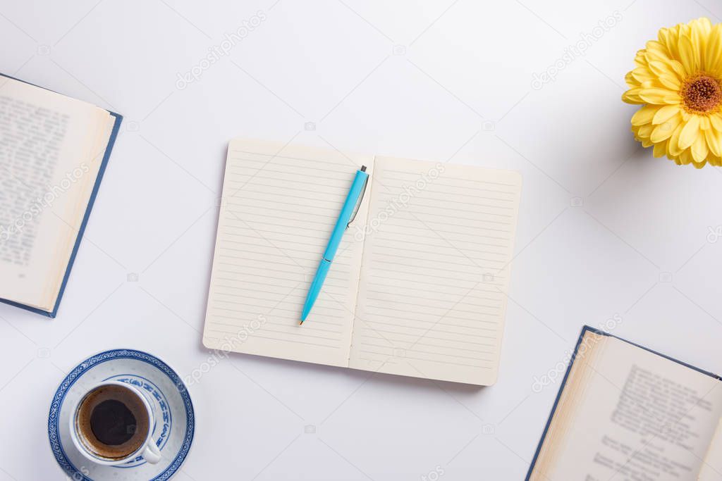 Planning concept. Open notebook and books, cup of coffee, flower, on white background. Flat lay, top view, copy space.