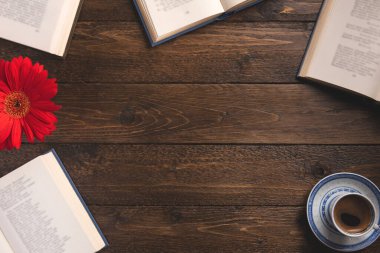 Cozy composition with books. Open books, cup of coffee, flower, on wooden background. Flat lay, top view, copy space.