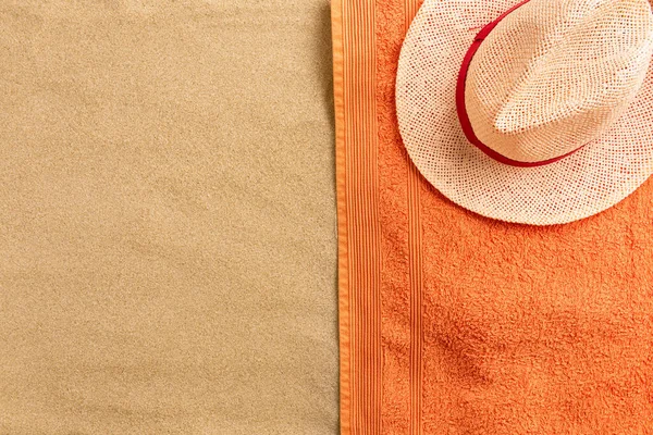 Top view of sandy beach with towel frame and summer accessories. Background with copy space and visible sand texture. Border composition made of towel