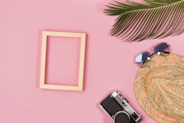 Travel vacation background concept. Sunglasses, hat, camera, palm leaves on pink background. Top view, copy space. Flat lay.