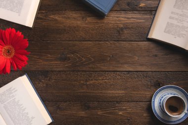 Cozy composition with books. Open books, cup of coffee, flower, on wooden background. Flat lay, top view, copy space.