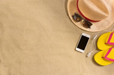 Yaz tatili kompozisyonu. Şapka, akıllı telefon ve arka planda parmak arası terlikler. Gölgeli sert bir ışık. Yaz arkaplanı.
