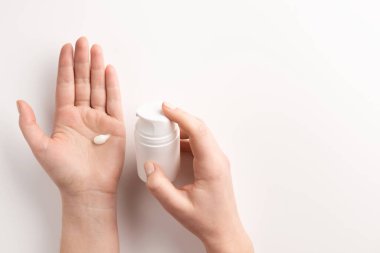 Beyaz arka planda, izole edilmiş krema kabı olan kadın elleri. Düz konum, üst görünüm, kopyalama alanı. Organik kozmetik konsepti.